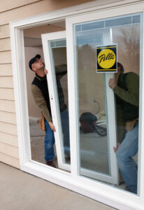 Two technicians installing a new sliding glass patio door.