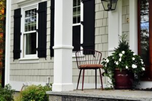 Beige shake shingle siding on home with black shutters and white trim.