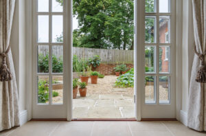 A set of open, white French patio doors looking out into a backyard.