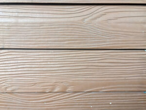 A close-up of brown lap siding with a natural woodgrain texture.